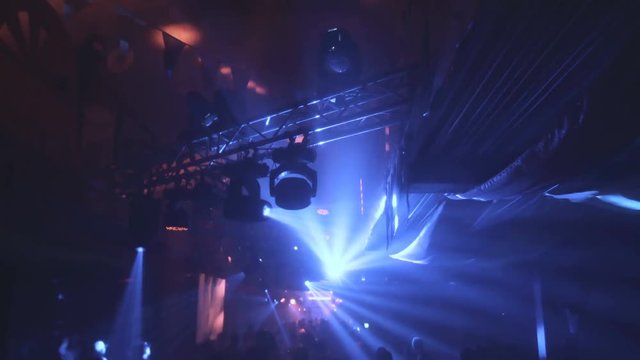Lot of people clapping at rave party. Here is footage of people crowd partying at a concert or a night club. You can see dark silhouettes dancing, jumping and waving hands in front of stage.