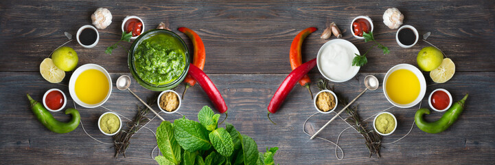 Sauces, spice, herbs, oil, condiments, seeds,cream, vegetables, lime, peppers, dried herbs, bowls, spoon on rustic wooden table. Selective focus. Wide panoramic image.