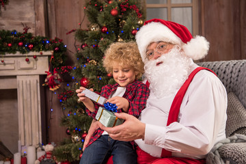Obraz na płótnie Canvas Santa Claus with kid on knees