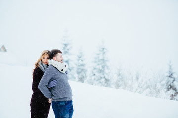 Pregnant lady hugs her man tender standing with him on snowy road