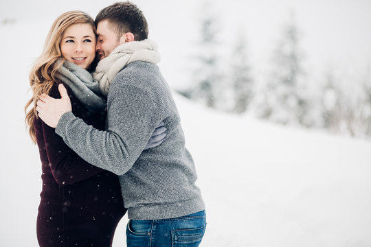 Man hugs beautiful pregnant lady tender standing on snowy road