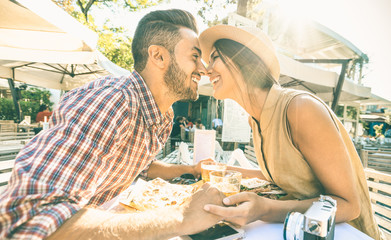 Couple in love kissing at bar eating local delicacie on travel excursion - Young happy tourists enjoying moment at street food restaurant - Relationship concept with lovers at first date - Warm filter