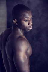 Fototapeta na wymiar African American bodybuilder young man, naked muscular torso, on dark background