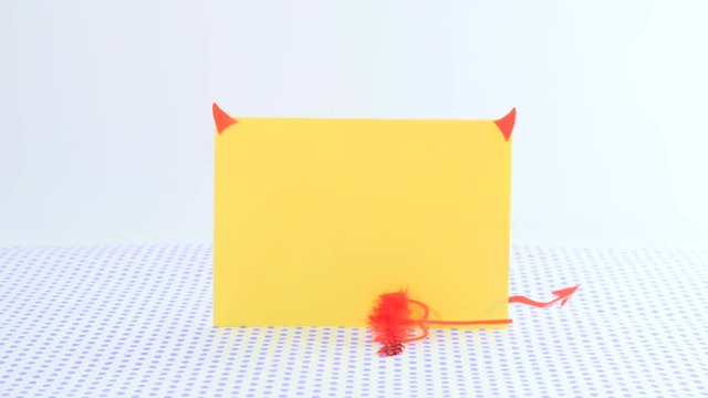 The paper in form of devil with horns and a trident on a dotted background