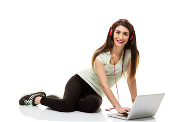 Happy girl listening to the music with laptop.