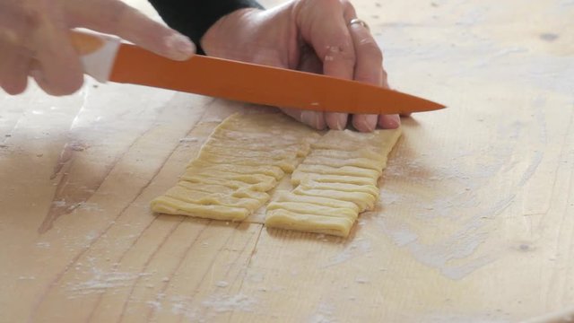 expert hand cutting fresh dough to make fettuccine