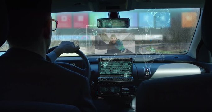 A man driving a technological and futuristic machine in which holograms appear for a driver assistance and video calls. Concept of machines of the future, driving safety, technology and transport
