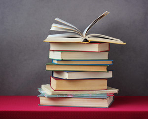 stack of books on the table with a red tablecloth.