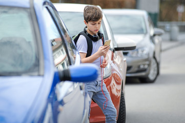 Kind spielt mit seinem smartphone auf der Straße und achtet weder auf den Verkehr, noch auf Autos