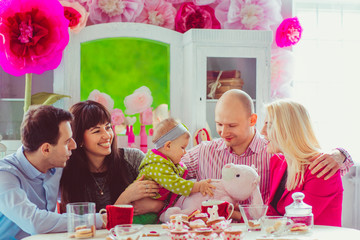 Joyful young couples and little girl have fun at dinner table