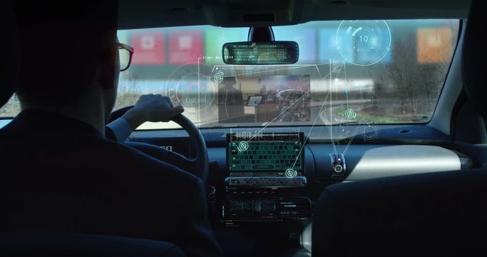 A man driving a technological and futuristic machine in which holograms appear for a driver assistance and video calls. Concept of machines of the future, driving safety, technology and transport