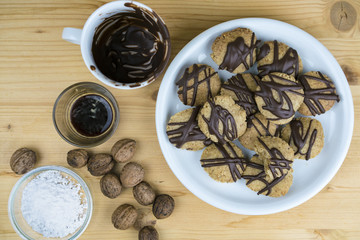 Tasty homemade walnut cookies displayed on a plate with an assortment of ingredients used in the baking of the recipe alongside, viewed from above