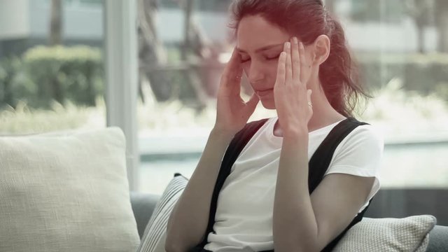 Young woman with headache, close up. Businesswoman having a headache and massaging her head