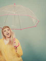 Happy woman wearing raincoat holding transparent umbrella