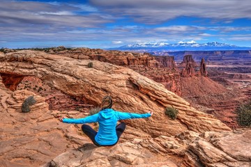 Young woman meditating at cliff by Mesa Arch. Canyonlands National Park. Moab. Utah. United States.
