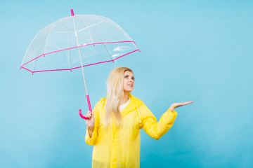 Woman wearing raincoat holding umbrella checking weather