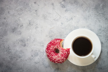 Donut and cup of coffee at concrete table. Top view copy space