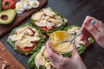 girl chef making sandwich in rustic style with turkey meat and chicken and vegetables