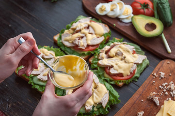 girl chef making sandwich in rustic style with turkey meat and chicken and vegetables