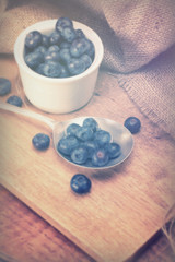 Pot of blueberries with spoon on a rustic background