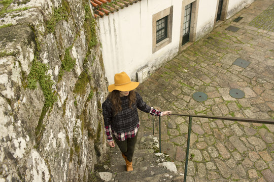 Young woman in yellow hat walking up stone  steps