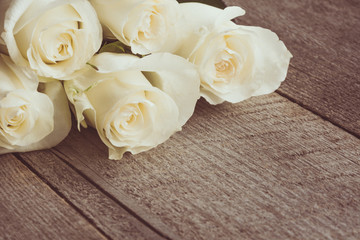 Soft full blown white roses as a neutral background on wooden board. Selective focus. Toned image.