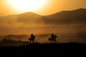 Fototapeta na wymiar Two men running horses silhouette