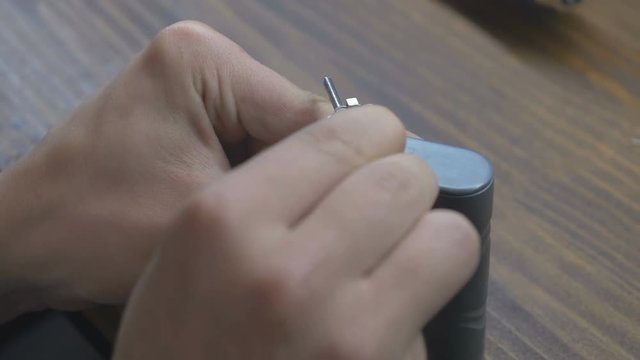 Close-up - the man corrects the spring with screwdriver in vape