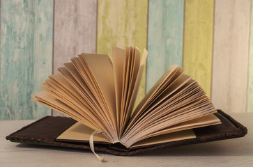 the book is on the table in a leather binding