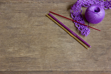 lilac clew of yarn with crochet hooks on a wooden table