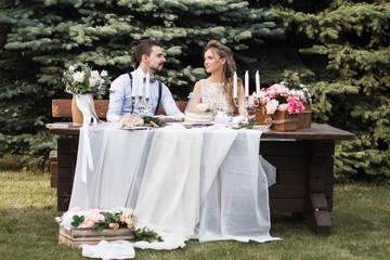 Wedding decoration in the style of boho, floral arrangement, decorated table in the garden. Against the background of the bride and groom embracing.