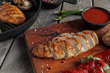 Grilled chicken fillet sliced on the board vegetables