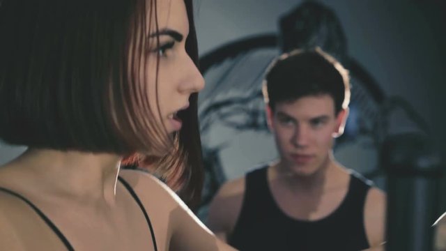 Pretty girl with trainer exercises on stepper in the gym in 4K