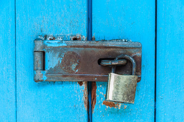 Old blue wooden door with rusty padlock and lock for background use