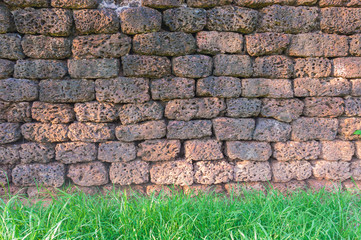 Old granite brick stone wall texture with green grass for background use