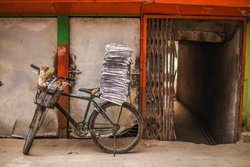 Fototapeta na wymiar old bicycle with stack of newspapers near rustic wall