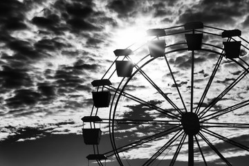Ferris wheel silhouetted against an intense sky.
