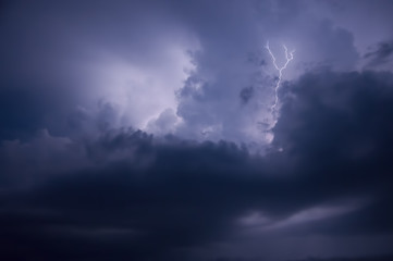 Naklejka na ściany i meble Thunderstorm, dark blue three-dimensional clouds illuminated by lightning flashes