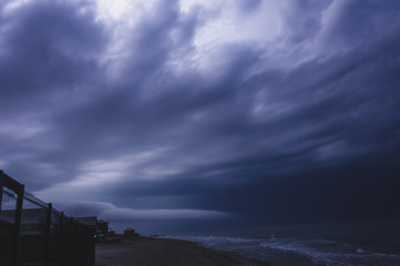 Thunderstorm over the sea, dark blue three-dimensional clouds illuminated by lightning flashes