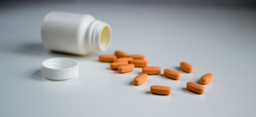 Open package of vitamins, orange pills scattered.