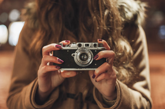 Hipster girl with retro camera taking photos outdoors