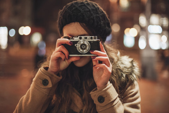 Hipster girl with retro camera taking photos outdoors