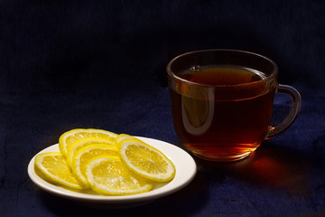 Чай в стеклянной чашке и лимоны на белой тарелочке