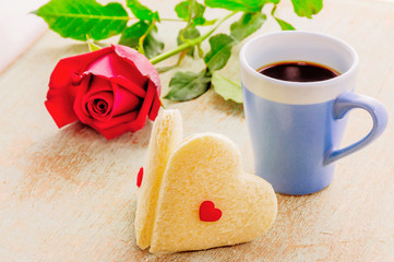 Couple of heart shape white bread with coffee cup and red rose. Photo is focused at the bread.