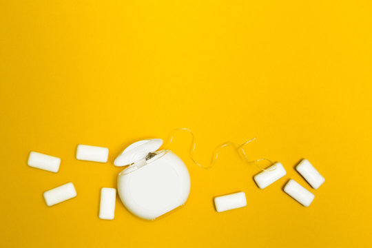 Chewing gum and dental floss on a yellow background. Space for text.