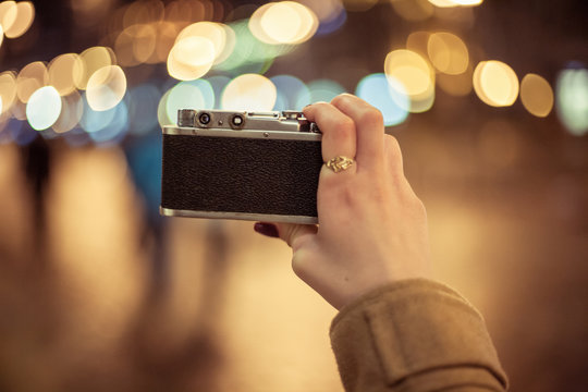 Hipster Girl Holding Retro Camera Taking Photos Of Night City, Point Of View Shot