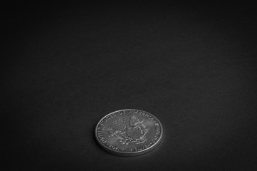 Silver one dollar coin laying on black surface - business concept, isolated.