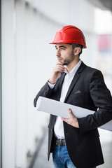 Man in hard hats at building with plans thinking