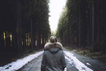 Junge Frau läuft allein auf einem einsamen Waldweg.