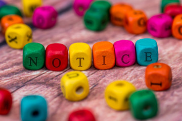 notice - word created with colored wooden cubes on desk.